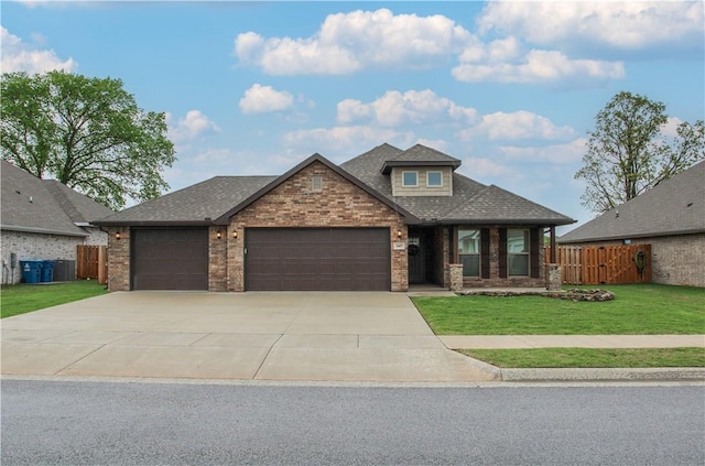 craftsman house with driveway, roof with shingles, a front yard, fence, and an attached garage