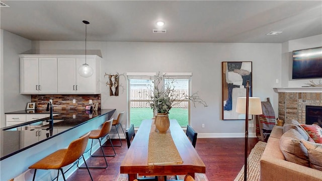 interior space with baseboards, a brick fireplace, dark wood finished floors, and visible vents