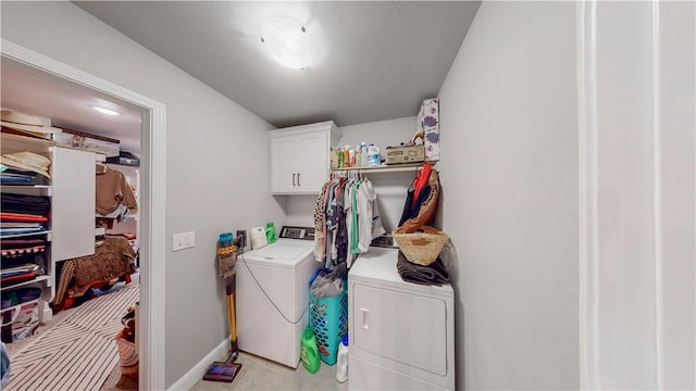clothes washing area with baseboards, cabinet space, and washing machine and dryer