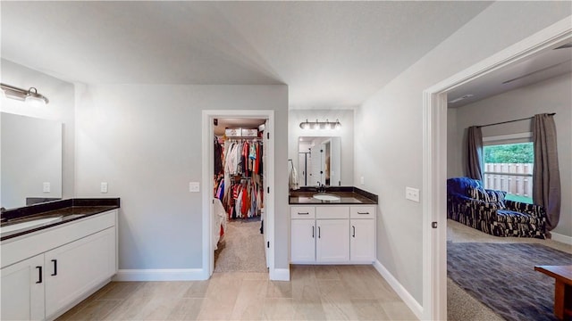bathroom featuring baseboards, a sink, and two vanities