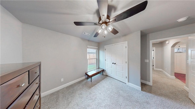 unfurnished bedroom featuring visible vents, arched walkways, baseboards, and light colored carpet