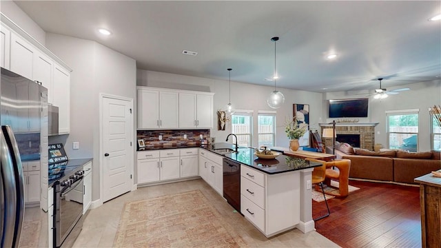 kitchen with a sink, a peninsula, open floor plan, a ceiling fan, and black appliances