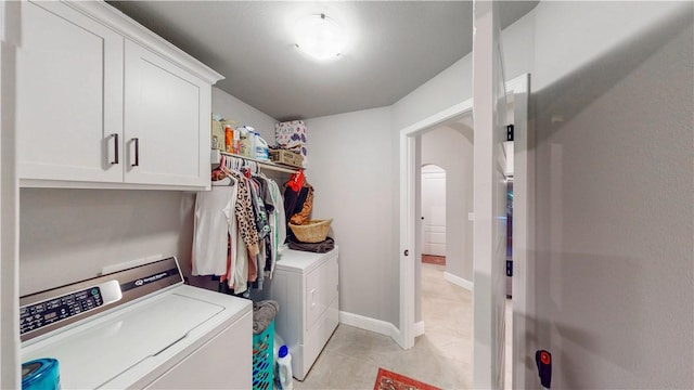 laundry room with washing machine and dryer, baseboards, arched walkways, cabinet space, and light tile patterned floors