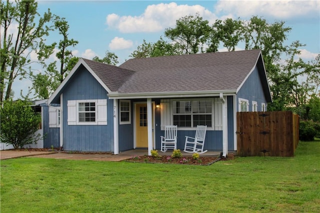 view of front of property with a porch, fence, a shingled roof, and a front lawn