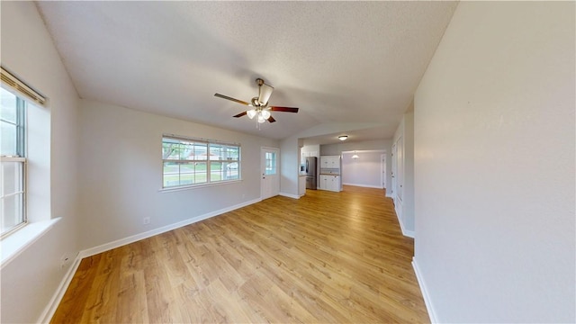 unfurnished living room featuring baseboards, ceiling fan, light wood-style flooring, and lofted ceiling