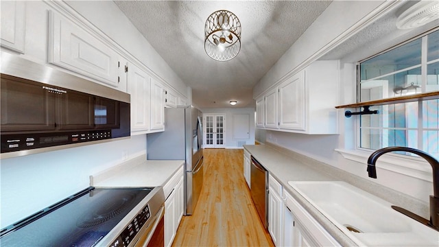 kitchen with light countertops, a sink, white cabinets, and stainless steel appliances