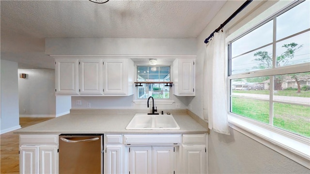 kitchen featuring white cabinets, a textured ceiling, a sink, and light countertops