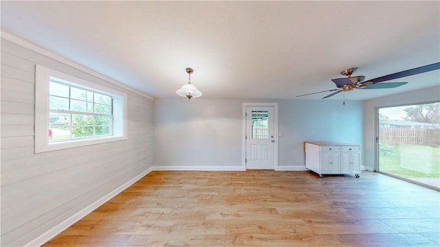 empty room with baseboards, a ceiling fan, light wood-style flooring, and a wealth of natural light