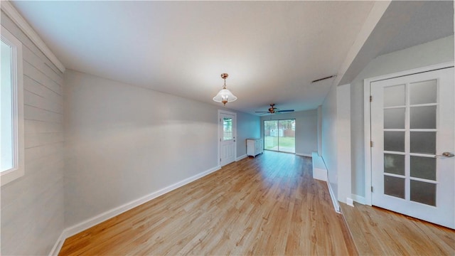 empty room featuring baseboards, visible vents, radiator heating unit, and light wood finished floors