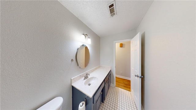 bathroom featuring a textured ceiling, visible vents, vanity, tile patterned floors, and toilet
