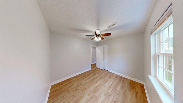 spare room featuring ceiling fan, visible vents, baseboards, and light wood finished floors