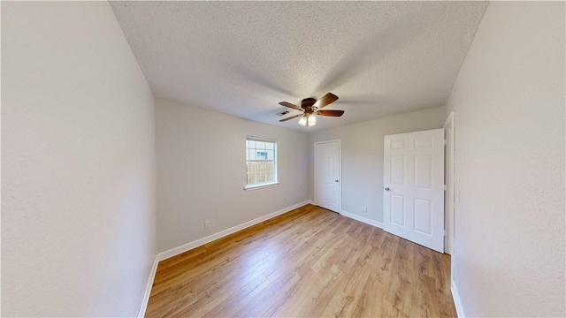 unfurnished bedroom with a closet, baseboards, ceiling fan, light wood-type flooring, and a textured ceiling