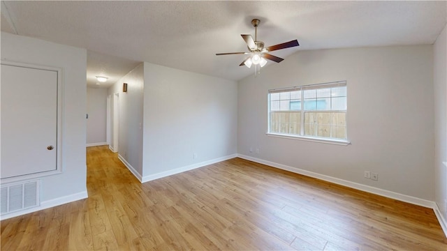 spare room with a ceiling fan, visible vents, baseboards, lofted ceiling, and light wood-style flooring