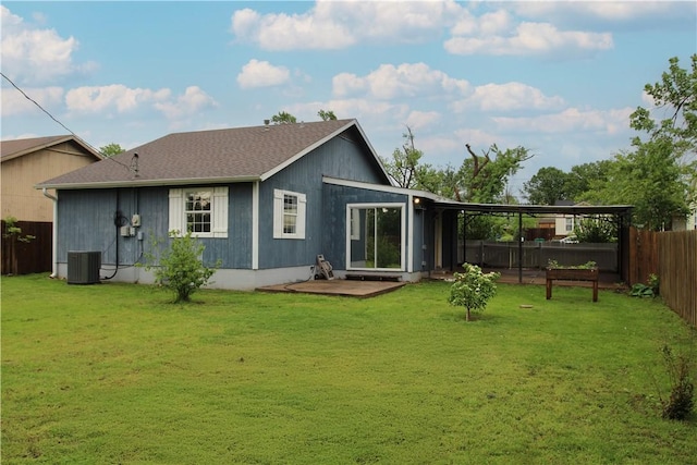 back of property with central air condition unit, a lawn, a shingled roof, and a fenced backyard