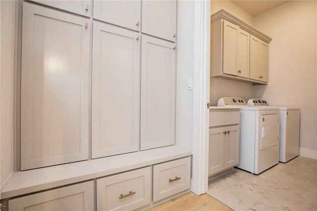 laundry area featuring light wood-type flooring, cabinet space, and washing machine and dryer