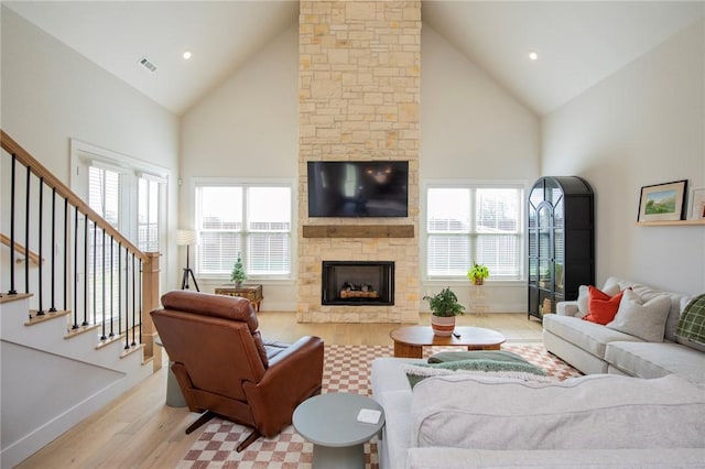 living room featuring stairs, high vaulted ceiling, wood finished floors, and a fireplace