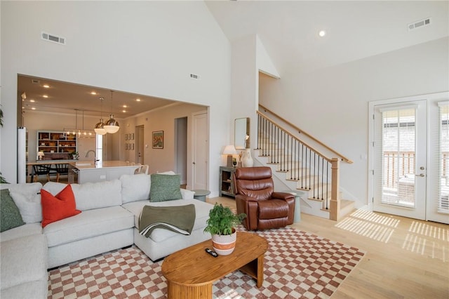 living area featuring visible vents, stairs, and high vaulted ceiling