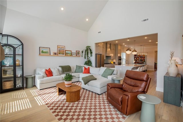 living room featuring visible vents, recessed lighting, light wood-style floors, and high vaulted ceiling