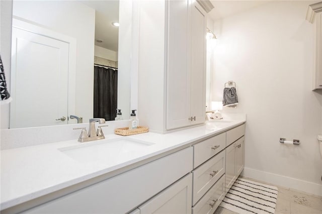 full bathroom featuring toilet, double vanity, baseboards, and a sink