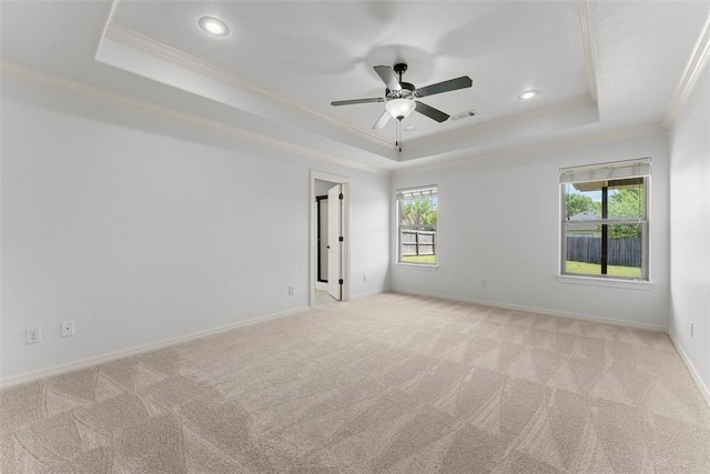 empty room featuring crown molding, visible vents, light carpet, and a raised ceiling