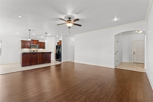 unfurnished living room with arched walkways, ceiling fan, recessed lighting, and light wood-style flooring