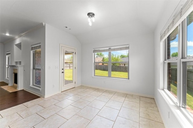 unfurnished room featuring visible vents, lofted ceiling, a fireplace, baseboards, and light tile patterned floors