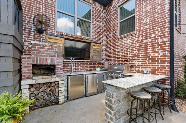 view of patio with an outdoor kitchen, outdoor wet bar, and a grill