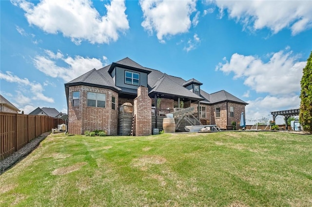 back of property featuring brick siding, fence, and a yard