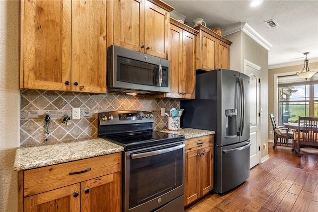 kitchen featuring decorative backsplash, visible vents, crown molding, wood finished floors, and stainless steel appliances
