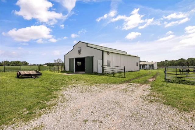view of pole building with fence, a lawn, and a rural view