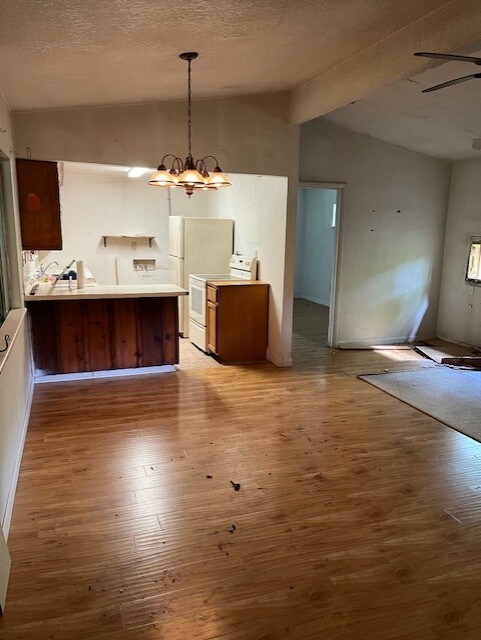 dining room featuring a textured ceiling, light wood-style flooring, and vaulted ceiling
