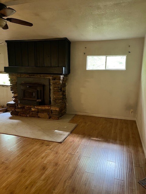 unfurnished living room featuring baseboards, a ceiling fan, and wood finished floors