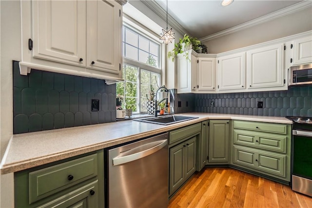 kitchen featuring appliances with stainless steel finishes, green cabinets, a sink, ornamental molding, and white cabinets