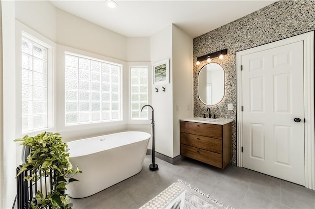 bathroom featuring a freestanding bath, vanity, tile patterned floors, and baseboards