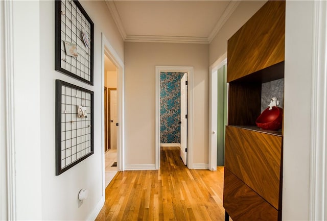 hallway featuring light wood finished floors, baseboards, and ornamental molding