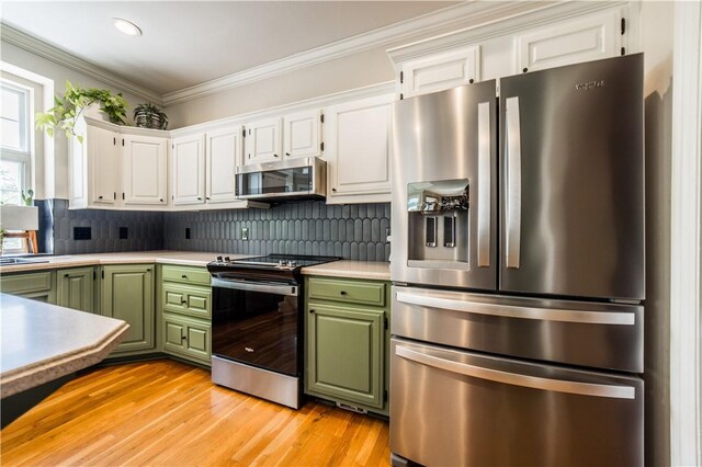 kitchen featuring stainless steel appliances, green cabinets, white cabinetry, crown molding, and tasteful backsplash