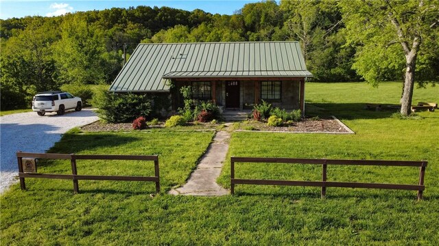 view of front of house with a standing seam roof, fence, a porch, and a forest view