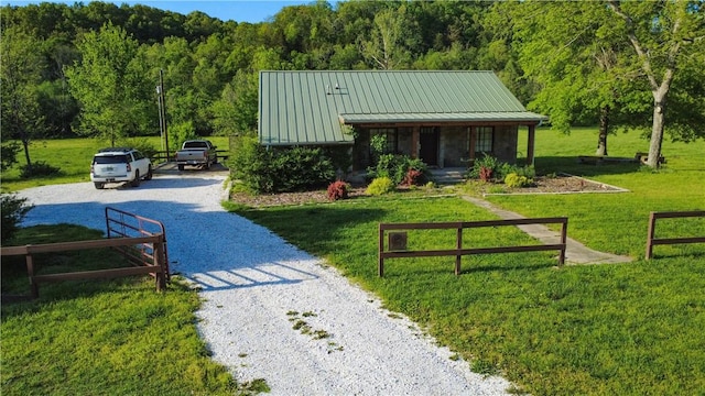 surrounding community with a lawn, a view of trees, and gravel driveway
