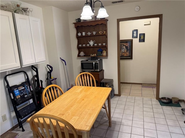 dining area featuring visible vents, light tile patterned flooring, and a notable chandelier