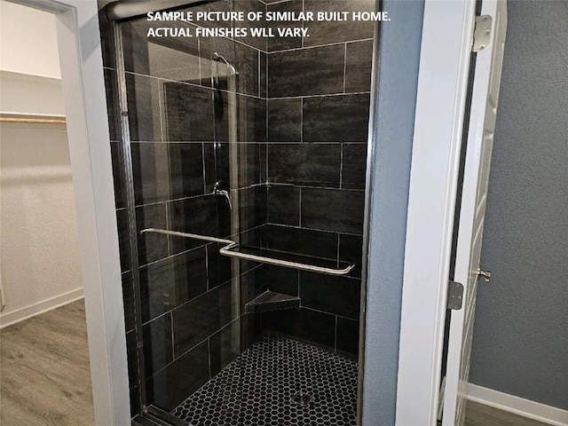 11 Exminster Ln, Bella Vista, AR 72714 - full bathroom with baseboards, a textured wall, a shower stall, and wood finished floors