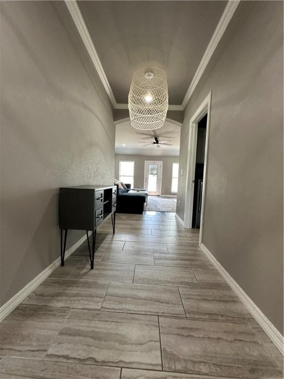 corridor featuring ornamental molding, baseboards, and wood finished floors