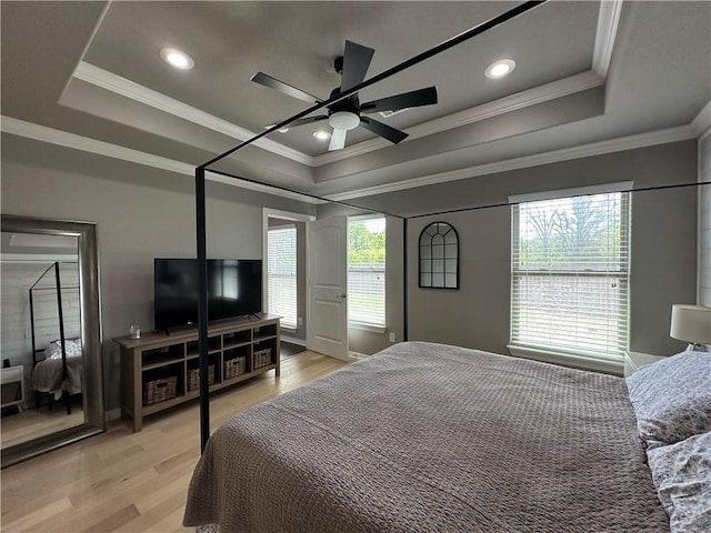 bedroom featuring a tray ceiling, light wood-type flooring, ornamental molding, ceiling fan, and recessed lighting