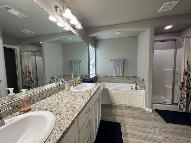 bathroom with a stall shower, a bath, double vanity, and recessed lighting