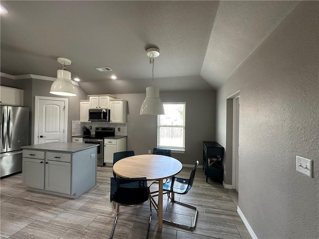 kitchen with appliances with stainless steel finishes, a center island, white cabinets, baseboards, and decorative light fixtures