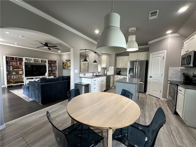 dining room with a ceiling fan, light wood-style flooring, recessed lighting, crown molding, and arched walkways