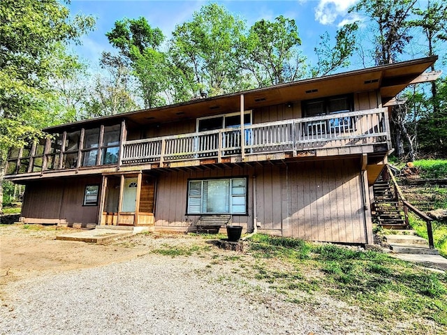 view of front of property featuring a sunroom, a wooden deck, and stairs