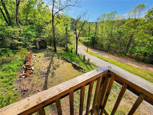 exterior space featuring an outbuilding, a storage shed, and a wooded view