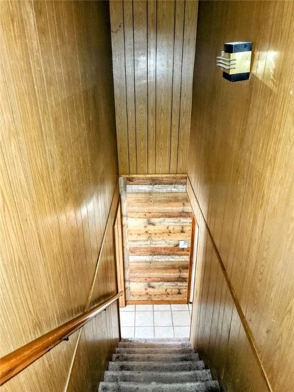 stairway featuring wood walls and tile patterned flooring