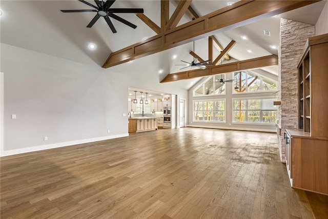 unfurnished living room with ceiling fan, wood finished floors, high vaulted ceiling, baseboards, and beamed ceiling
