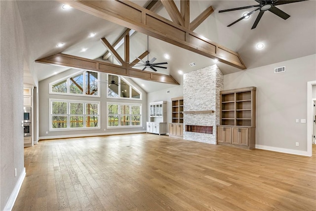 unfurnished living room with a ceiling fan, high vaulted ceiling, visible vents, and a stone fireplace